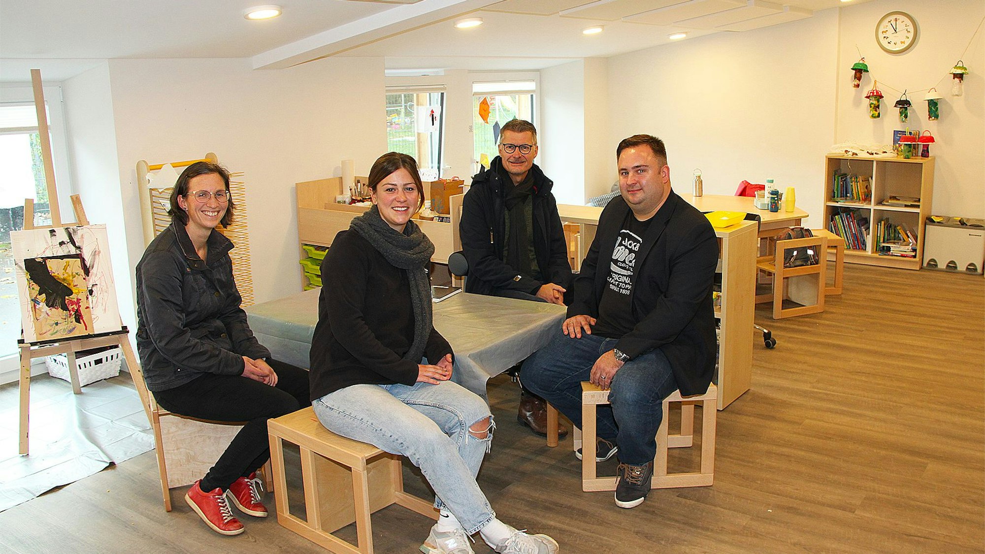 Die vier Genannten sitzen an einem Tisch im gemütlichen Gruppenraum des Kindergartens.