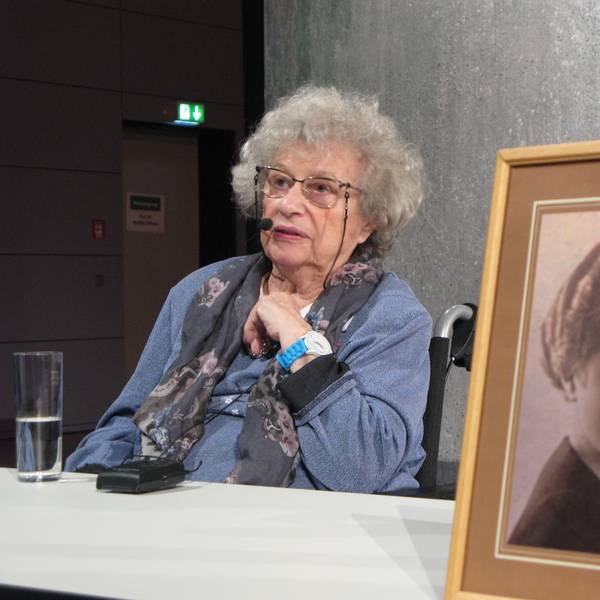 Tamar Dreifuss sitzt an einem Tisch, vorn steht eine gerahmte Fotografie ihrer Mutter.