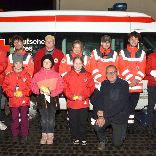 Gruppenbild mit den Mitgliedern des DRK-Ortsverbands Mechernich vor einem Rotkreuz-Kleinbus. Einige tragen Einsatzkleidung mit Reflektor-Streifen.