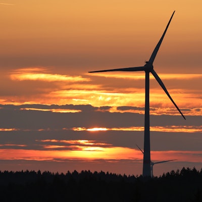 Das Bild zeigt ein Windrad in einem Wald auf dem Gebiet der Gemeinde Dahlem in der Abenddämmerung.