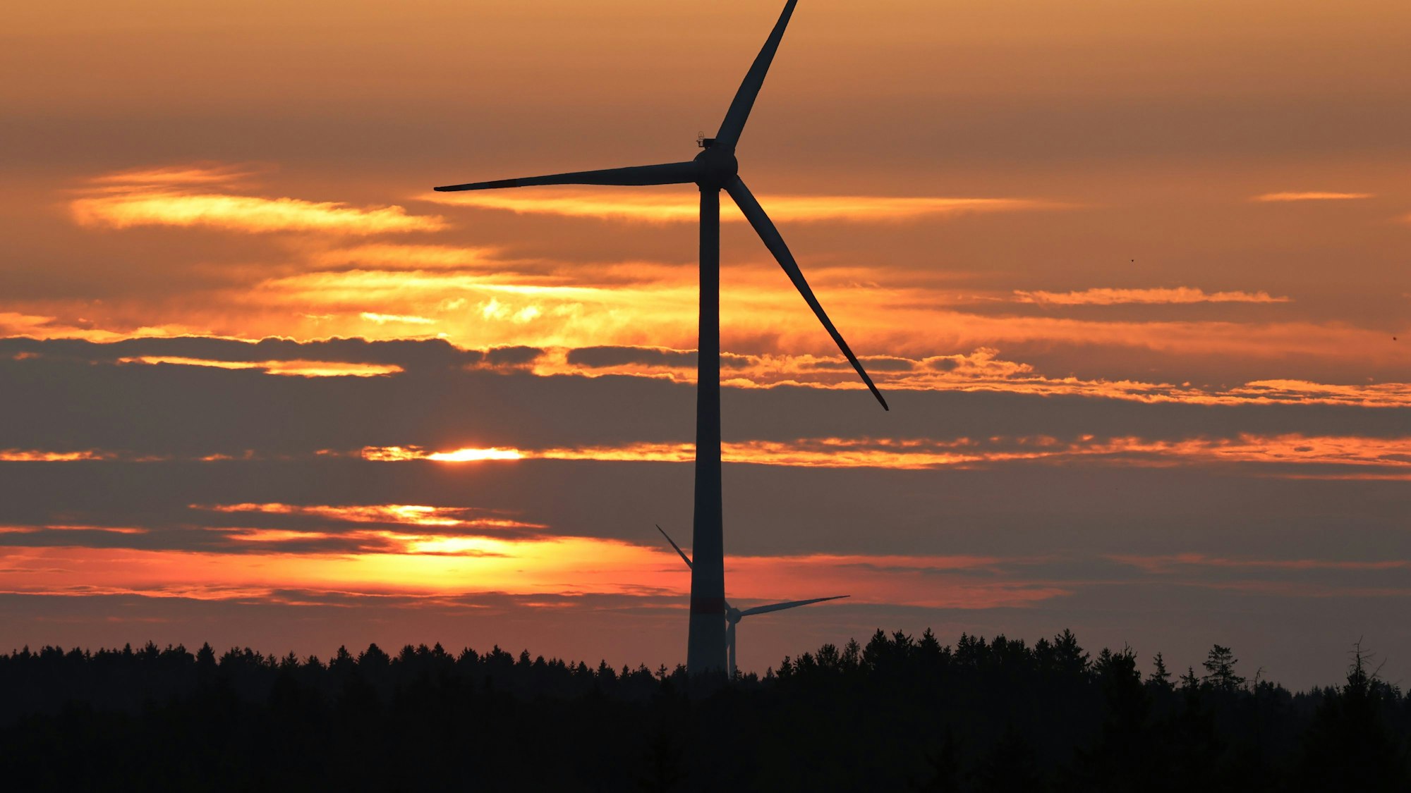Das Bild zeigt ein Windrad in einem Wald auf dem Gebiet der Gemeinde Dahlem in der Abenddämmerung.