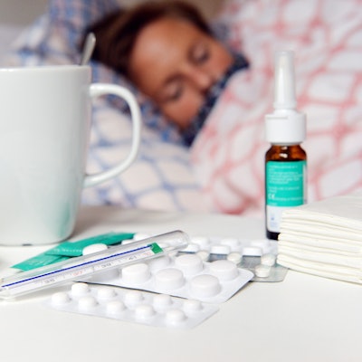 Medikamente und ein Fieberthermometer liegen auf einem Nachttisch.