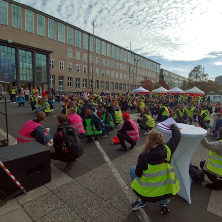 Teilnehmer und Teilnehmerinnen des Warnstreiks sitzen auf dem Boden