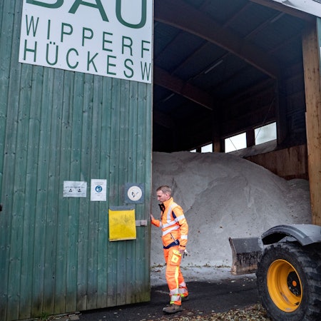 Ein Mitarbeiter des Bauhofs schiebt eine Hallentüre auf. Dahinter sind Berge von Streusalz zu sehen.