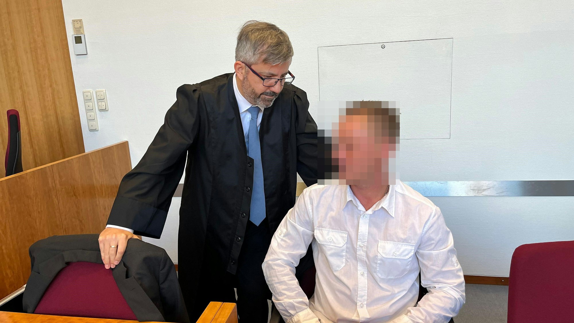 Ein Mann sitzt auf der Anklagebank. Neben ihm steht sein Anwalt.