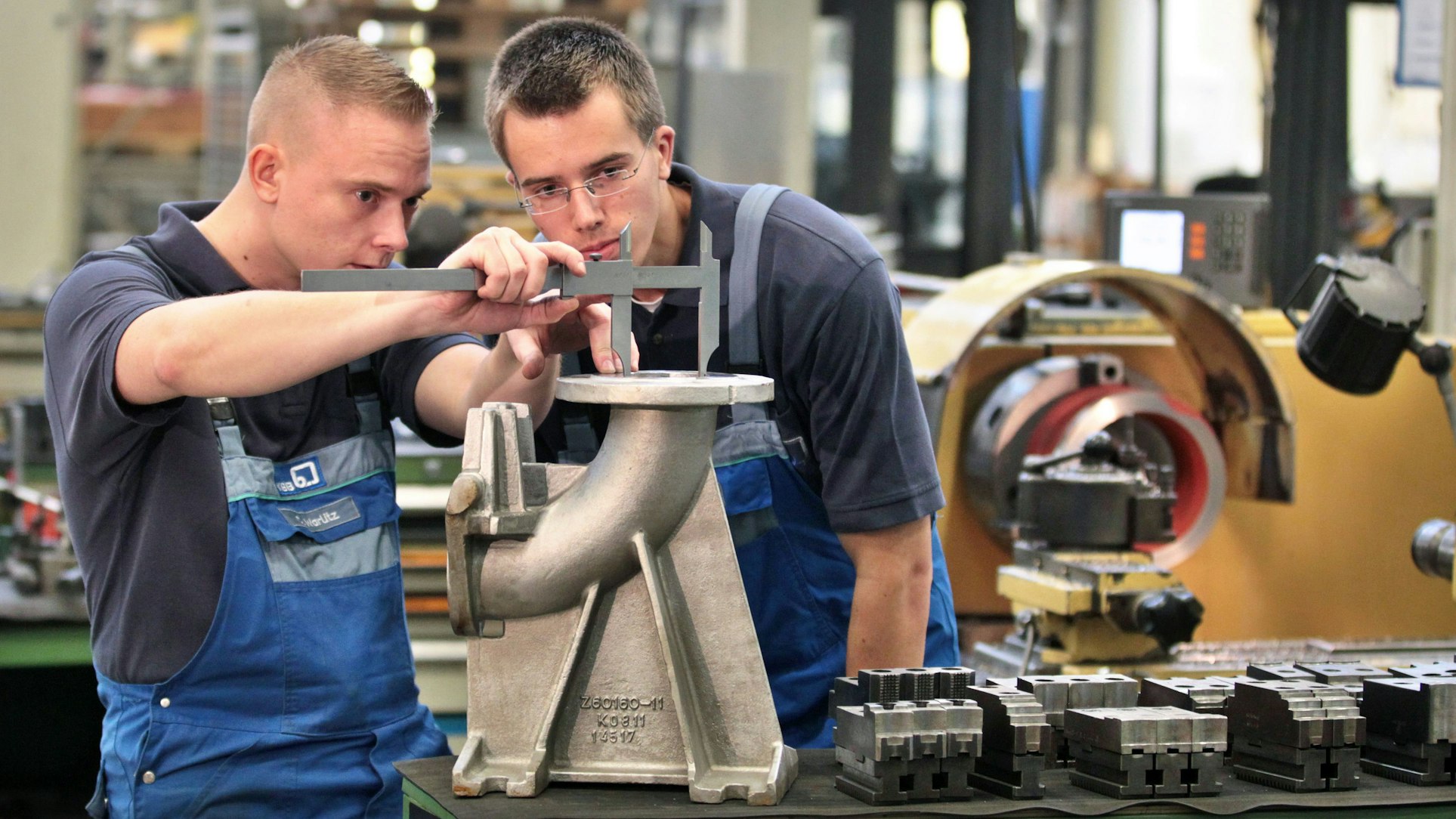 Ein Ausbilder prüft einen Auszubildenden zum Zerspanungsmechaniker an einem Flanschkrümmer beim Pumpenhersteller KSB AG in Halle (Saale).