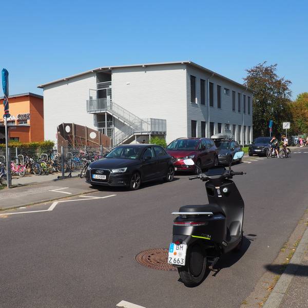 Im Hintergrund ist links ein Schulgebäude zu sehen, rechts ein Modulbau.