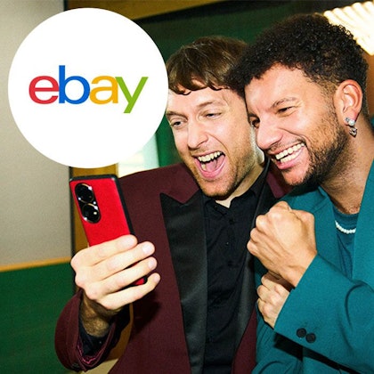 Zwei Männer schauen erfreut auf ein Handy.