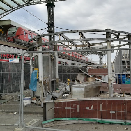 Trümmer der Currywurstbude hinter einem Bauzaun am Breslauer Platz.