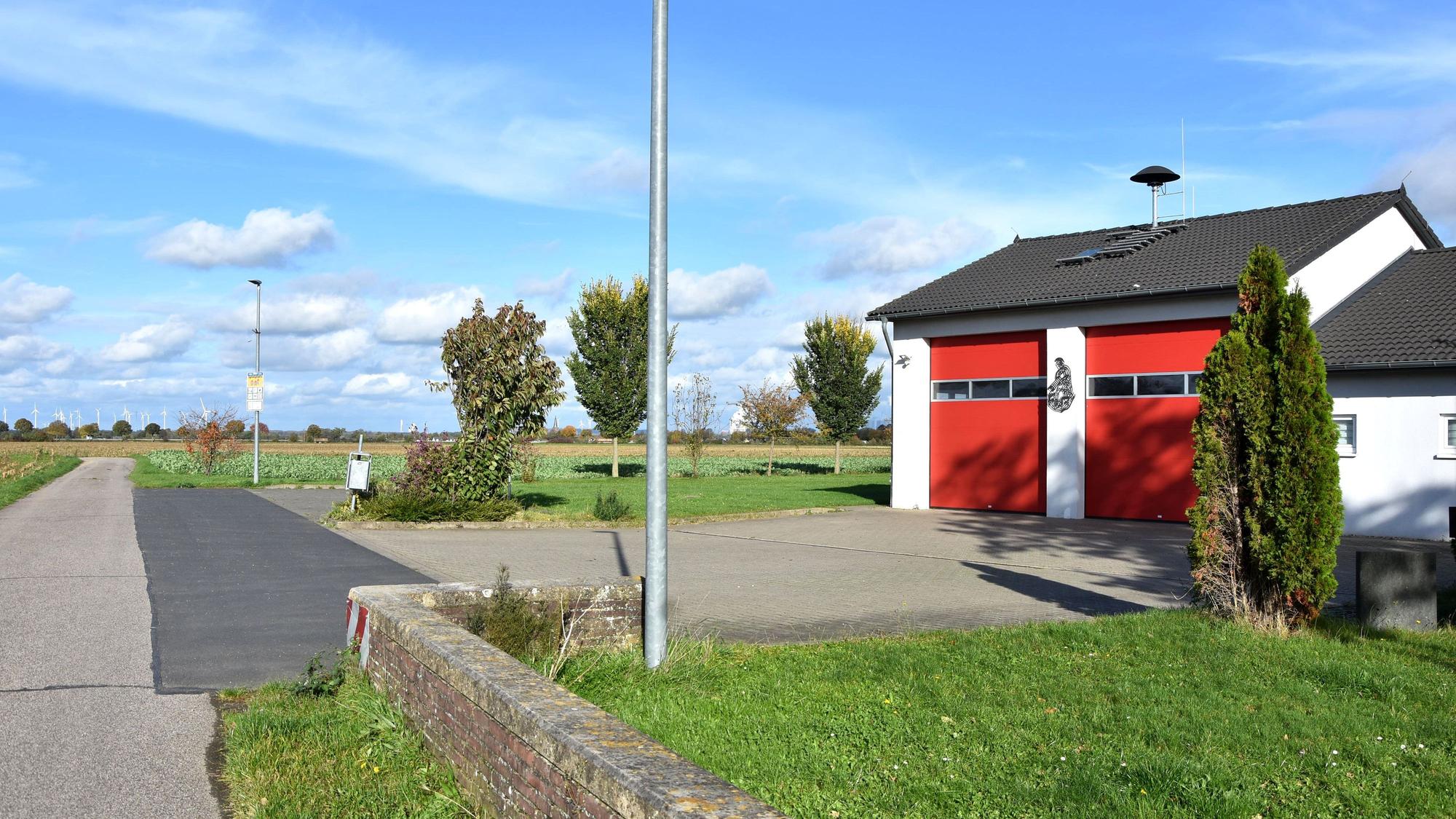 Ein Feuerwehrgerätehaus steht einsam an einem befestigten Wirtschaftsweg.