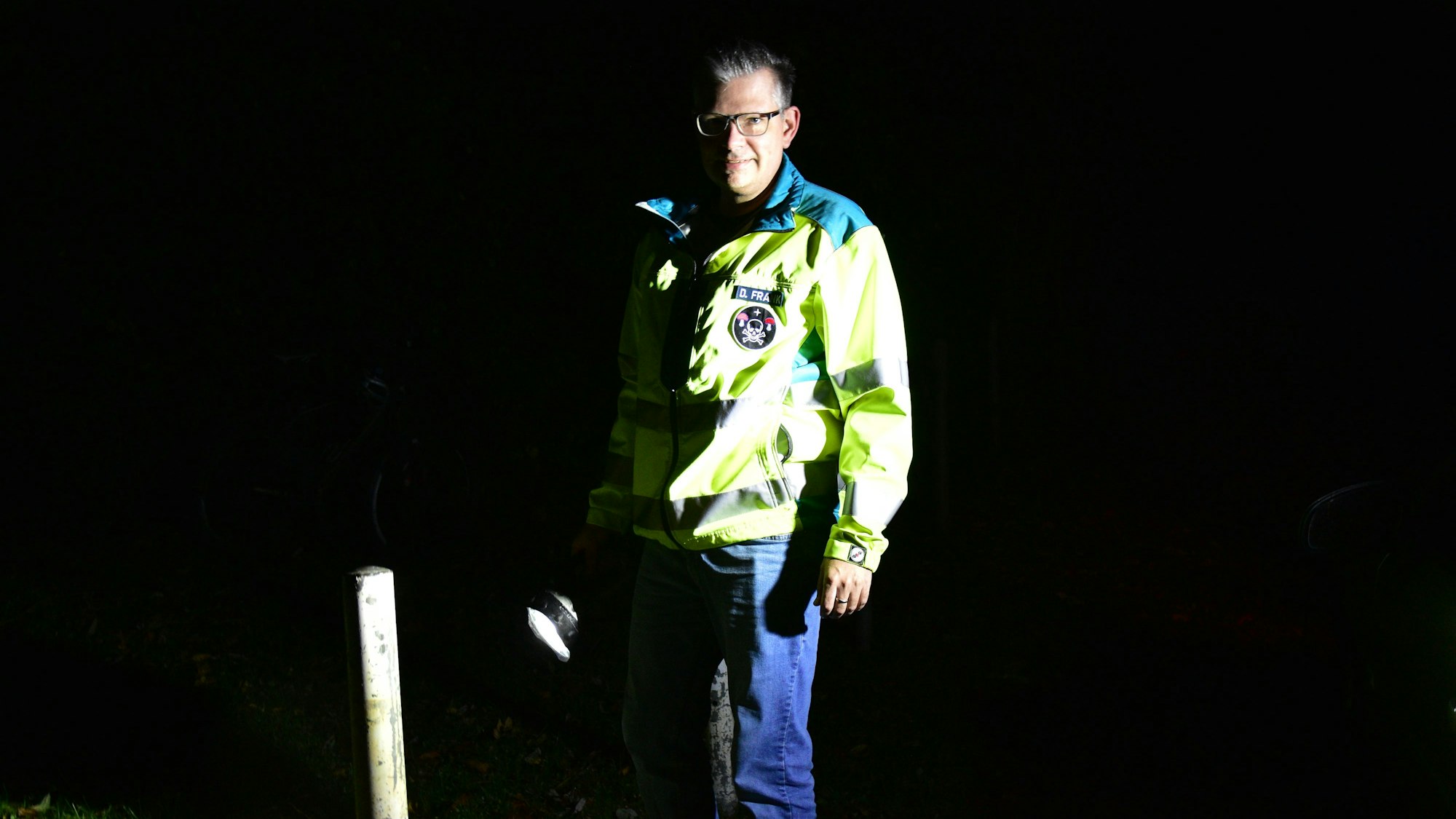 Daniel Frank mit reflektierender Rettungsjacke und Taschenlampe in der Dunkelheit.