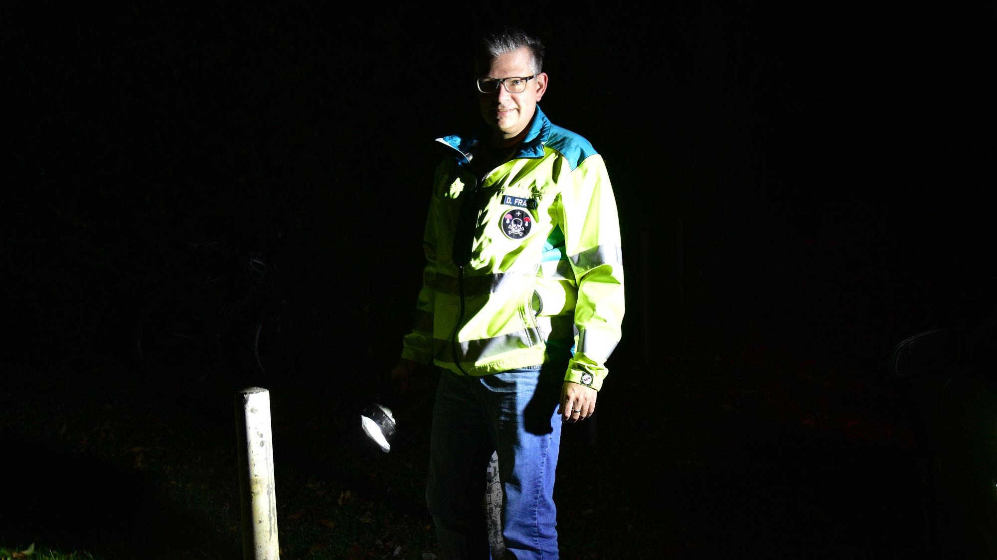 Daniel Frank mit reflektierender Rettungsjacke und Taschenlampe in der Dunkelheit.