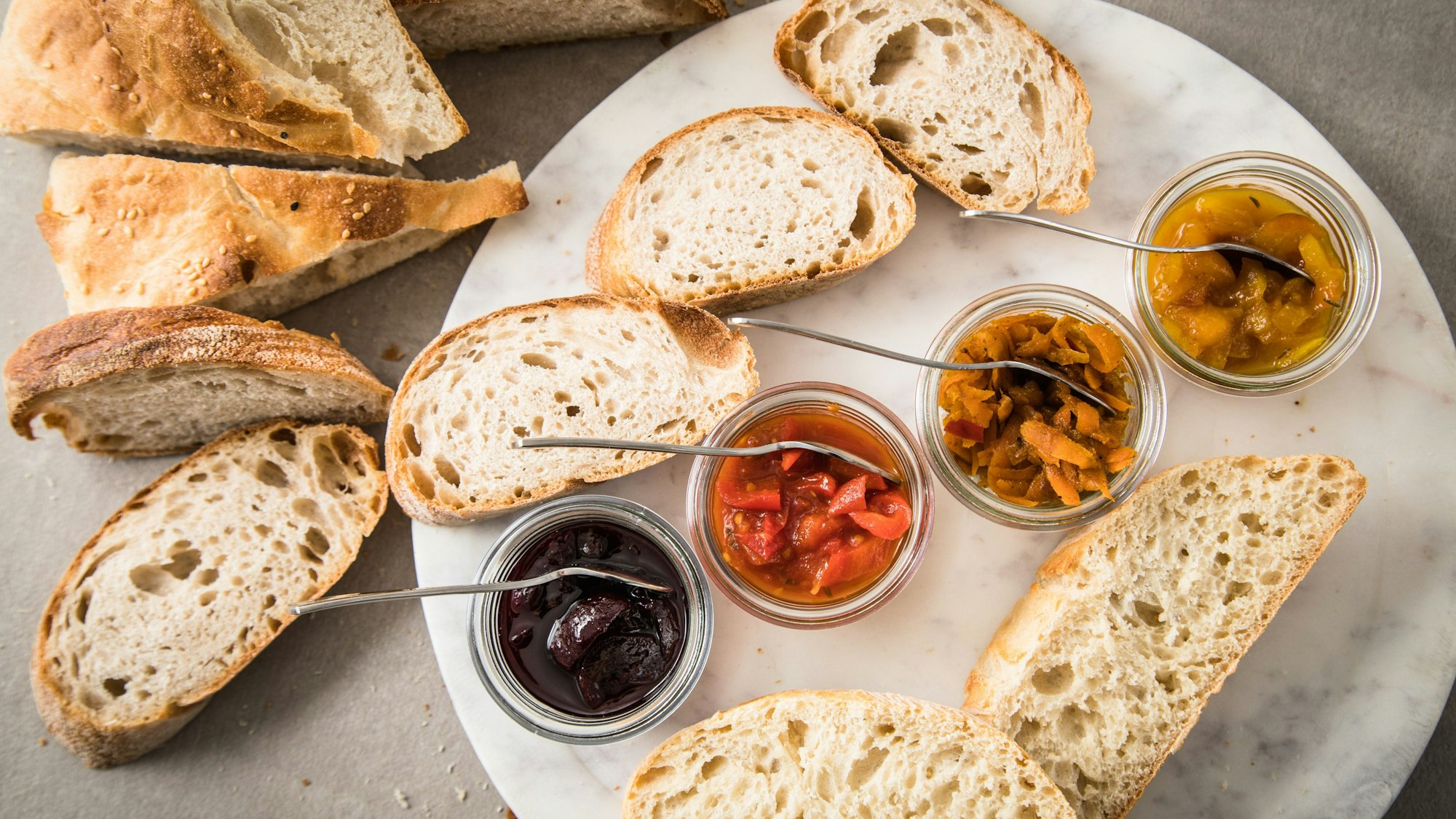 Brot und verschiedene Chutney-Arten liegen auf einem Teller.