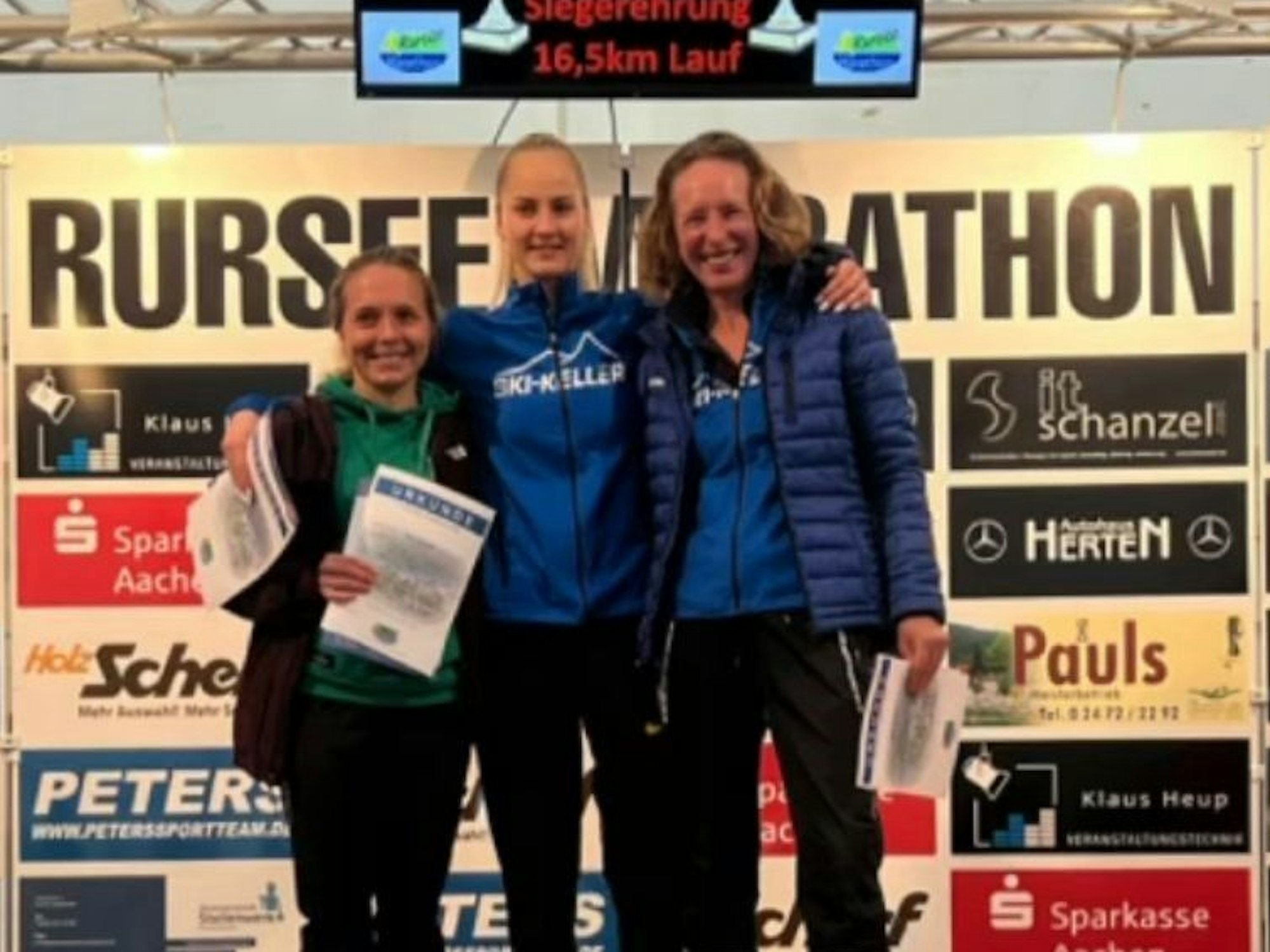 Die Siegerin des 16,5-Kilometer-Laufs nimmt auf dem Siegerpodest ihre beiden Kontrahentinnen in den Arm.