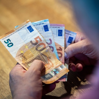 Ein älterer Mann sitzt an einem Tisch und zählt Geld.