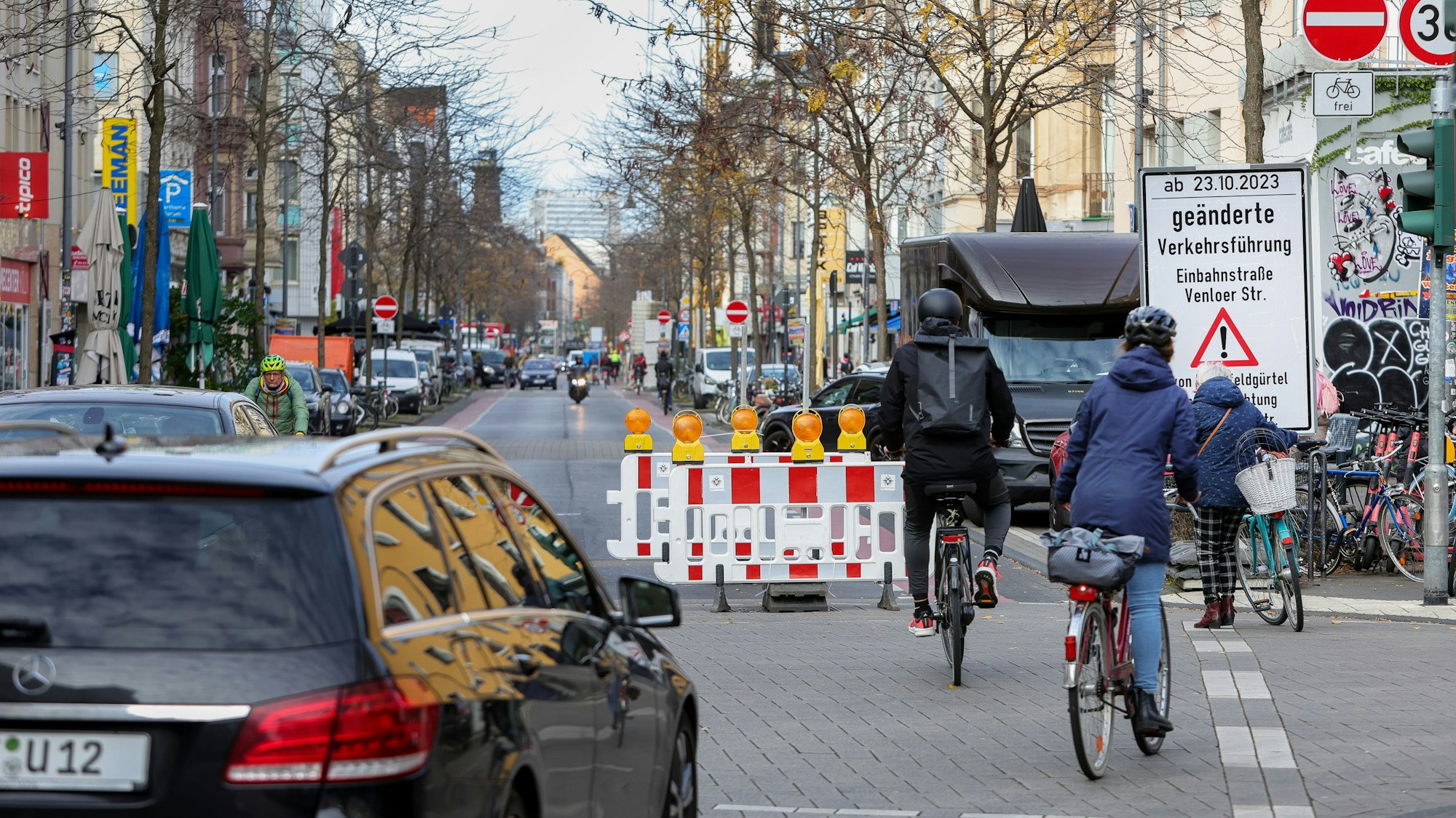 Radfahrer und ein Auto vor der Sperrung an der Kreuzung zur Piusstraße, wo die Venloer Straße zur Einbahnstraße wird