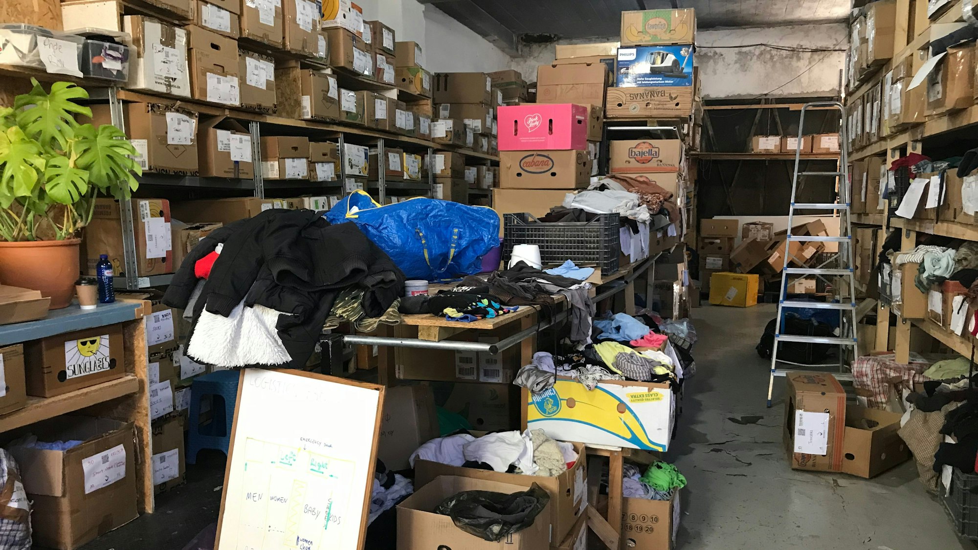 Zu sehen sind mehrere Regale mit Kartons und Kleidung.
