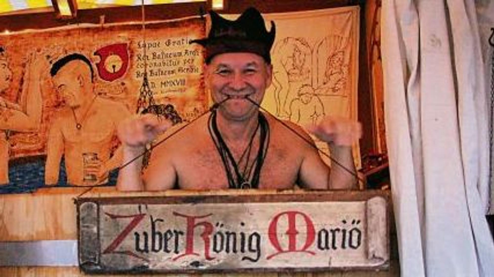 Mit freiem Oberkörper hockt der Zuberkönig Mariö in einem Badezuber aus Holz.