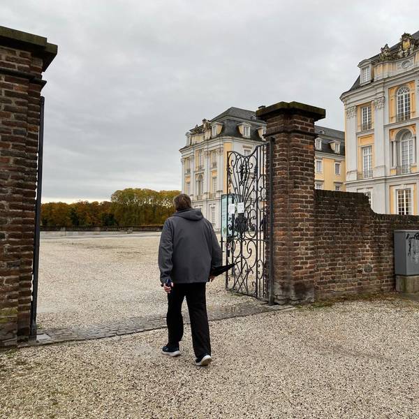 Zu sehen ist ein Spaziergänger, der den Park vor Schloss Augustusburg betritt.