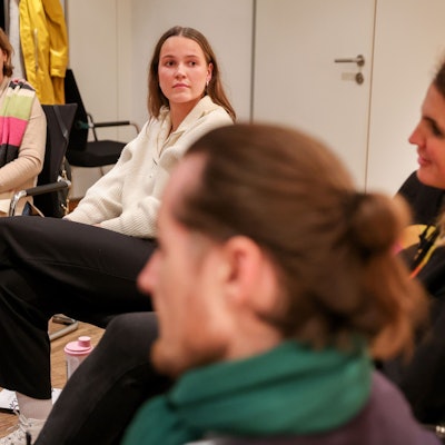 Emilie Vogeler trägt einen weißen Pulli und eine schwarze Hose und sitzt mit anderen Ehrenamtlichen bei einer Gesprächsrunde des Hospizvereins Mülheim.