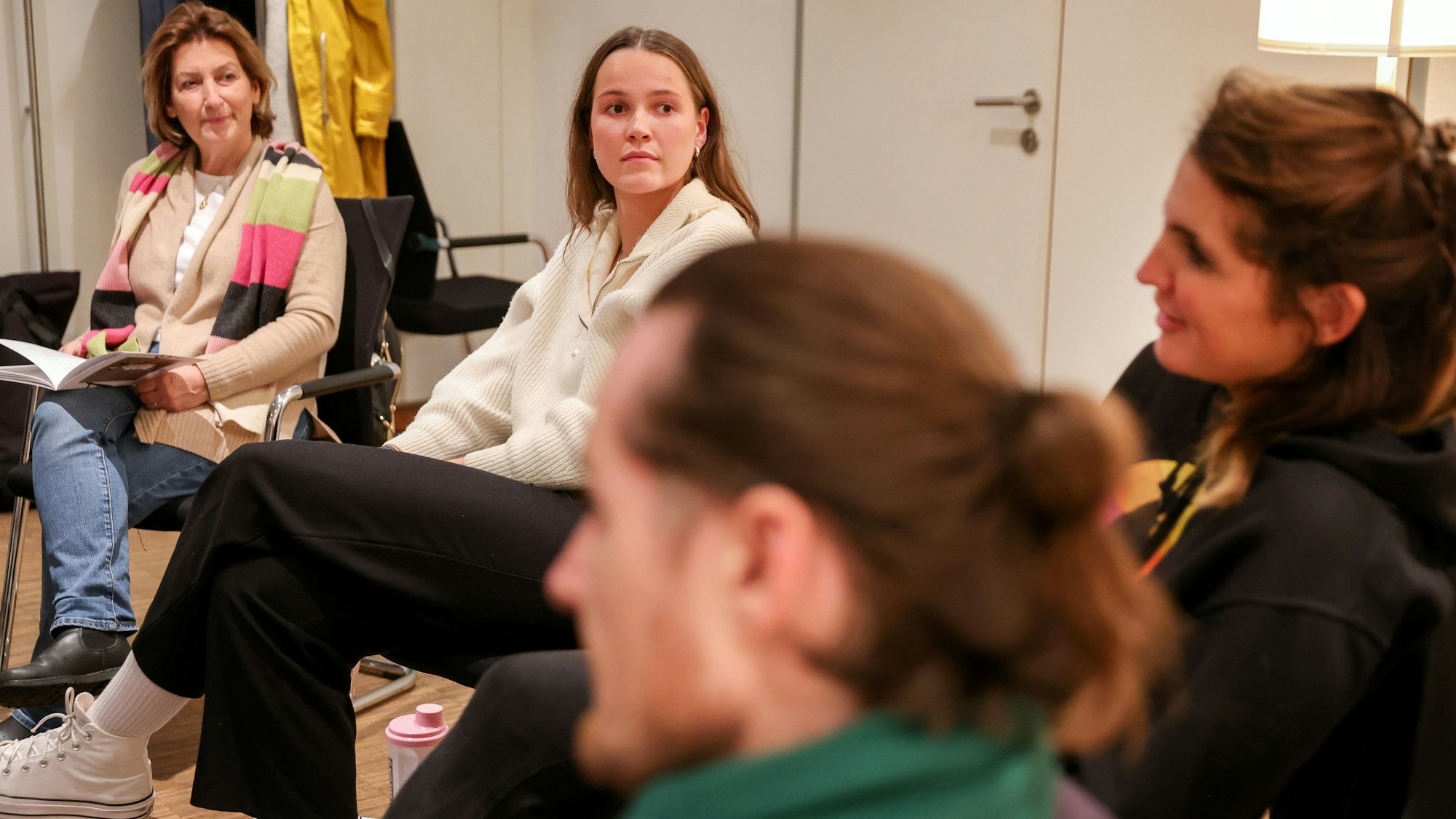 Emilie Vogeler trägt einen weißen Pulli und eine schwarze Hose und sitzt mit anderen Ehrenamtlichen bei einer Gesprächsrunde des Hospizvereins Mülheim.