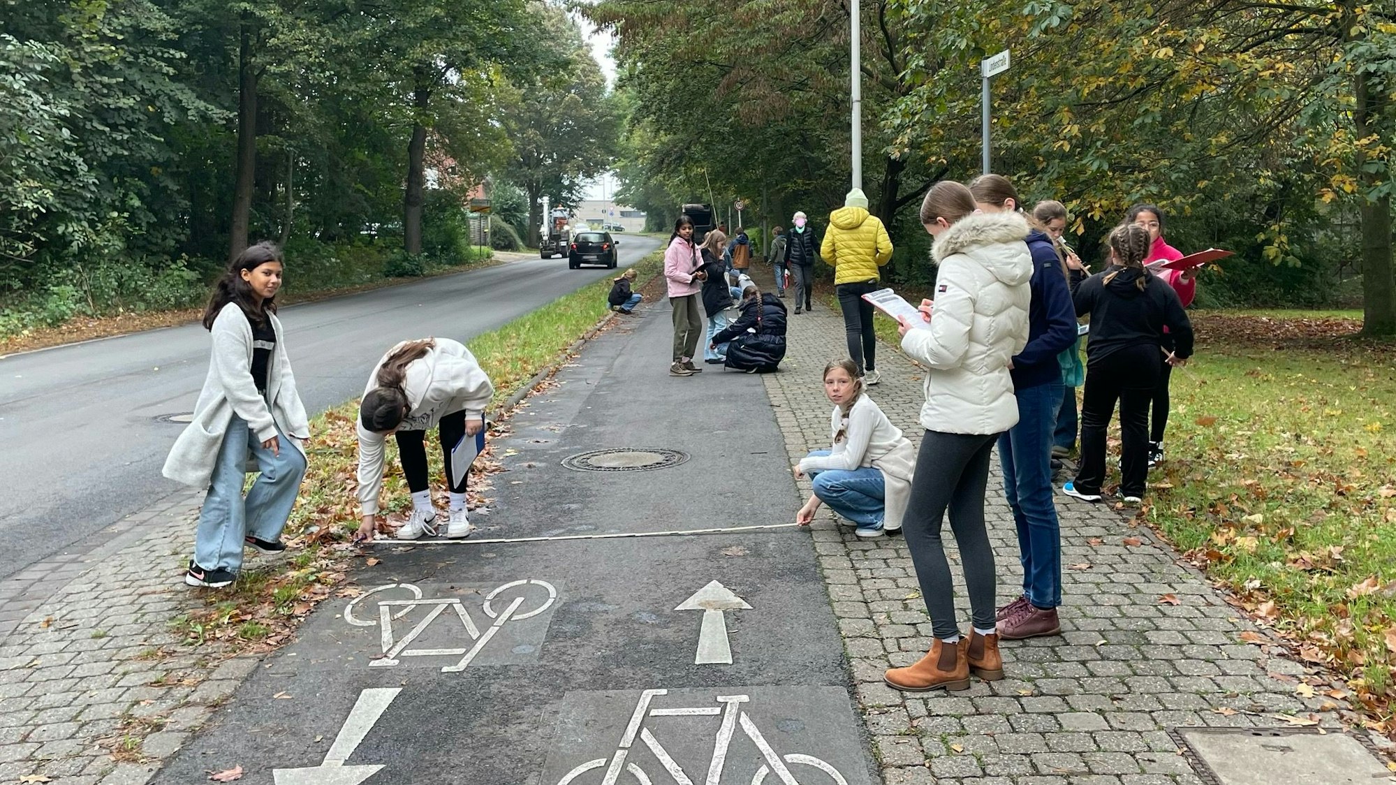 Auf dem Bild sind Schüler zu sehen, die einen Radweg ausmessen.
