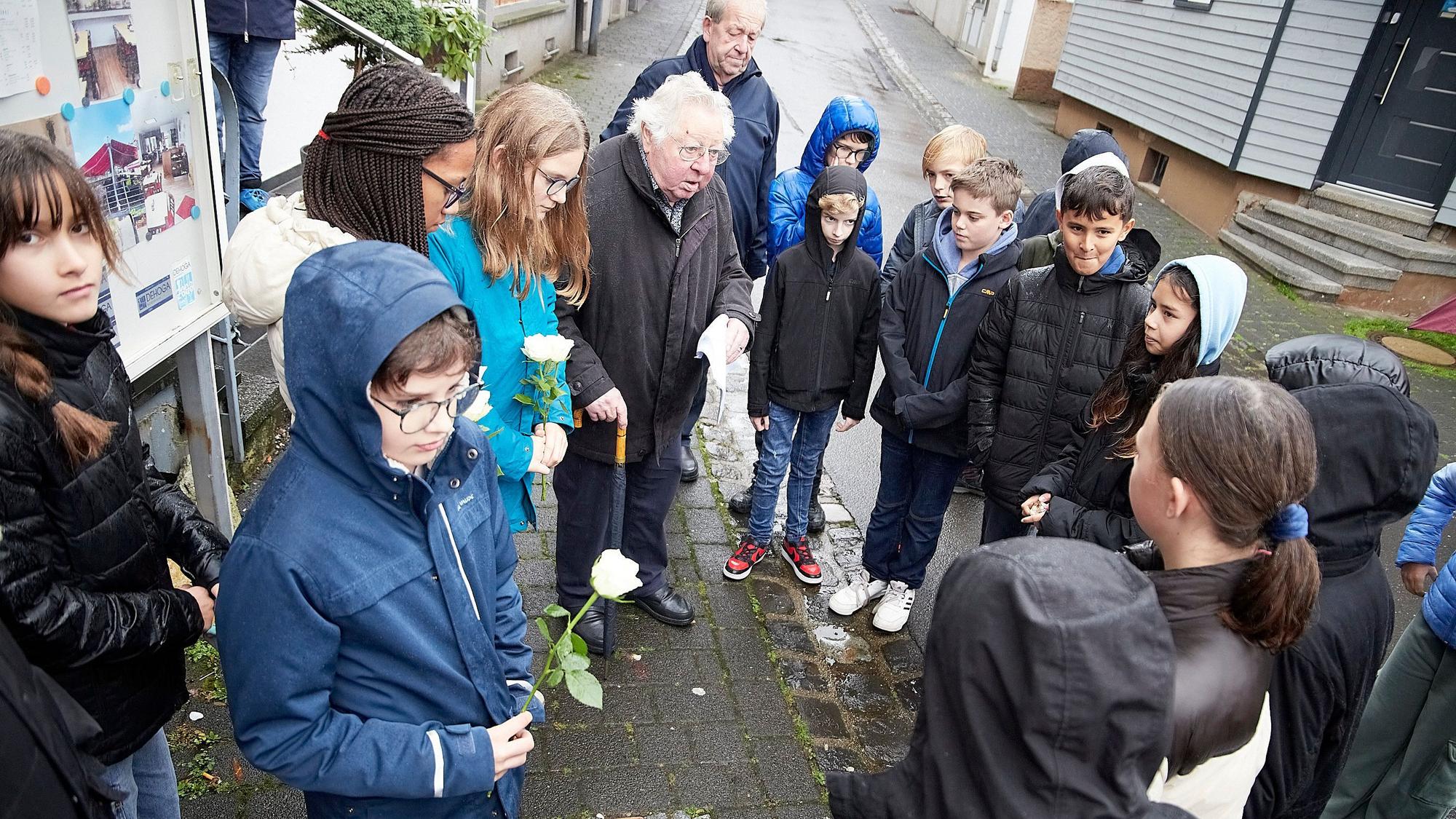 Alois Sommer mit einer Gruppe von Schulkindern. Einige tragen eine weiße Rose in der Hand.