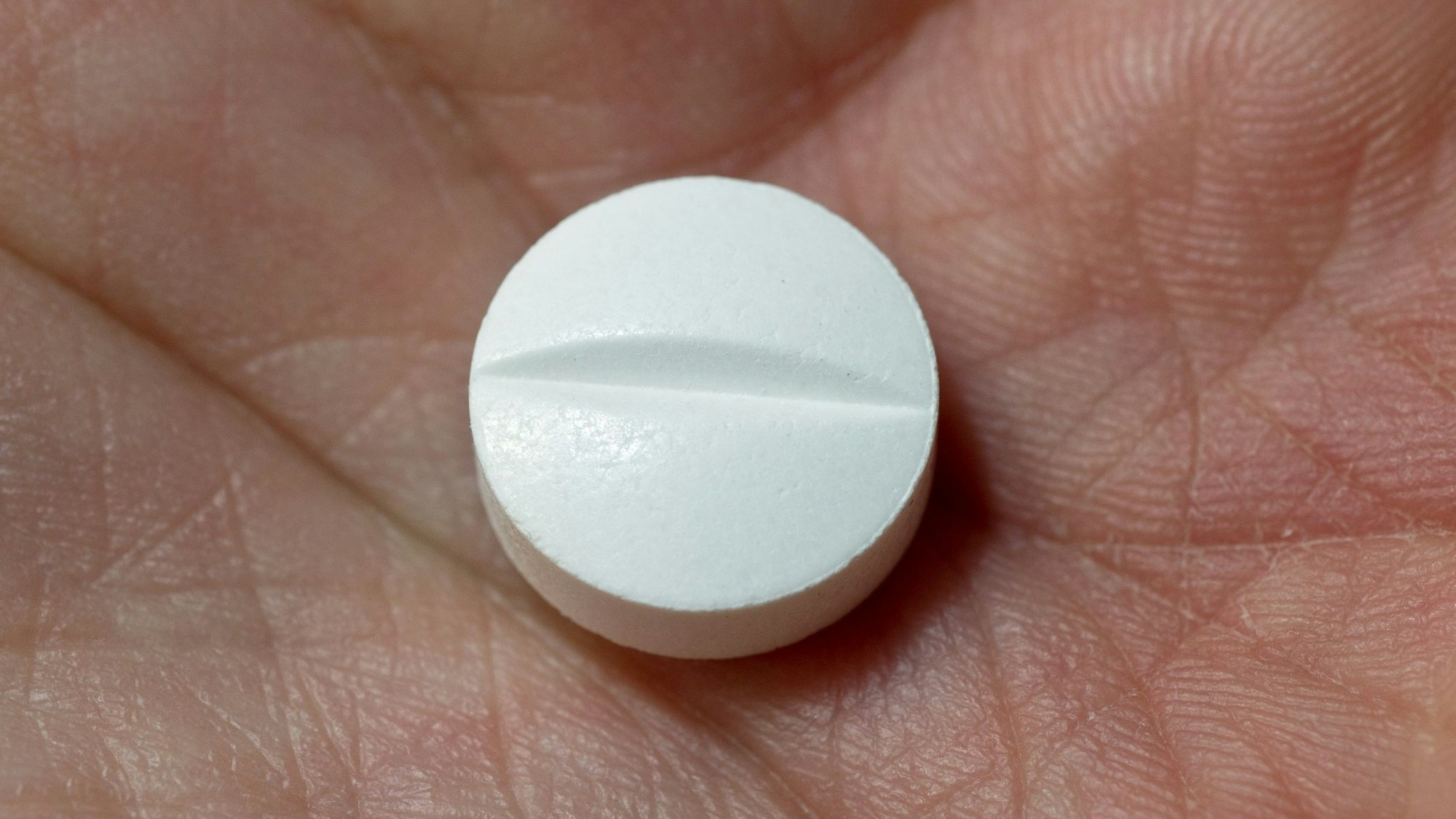 Auf der Hand einer Frau liegt eine Tablette, die den Wirkstoff Paracetamol enthält.