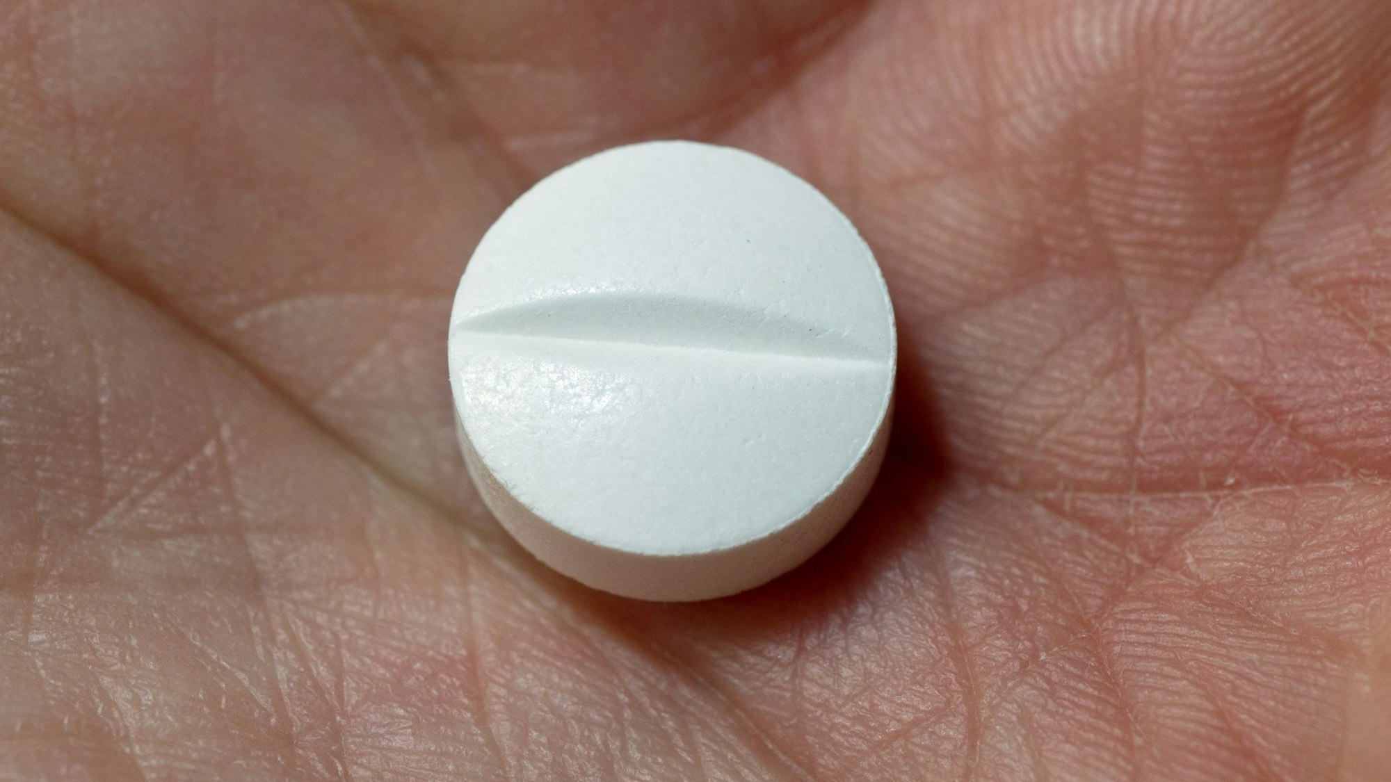 Auf der Hand einer Frau liegt eine Tablette, die den Wirkstoff Paracetamol enthält.