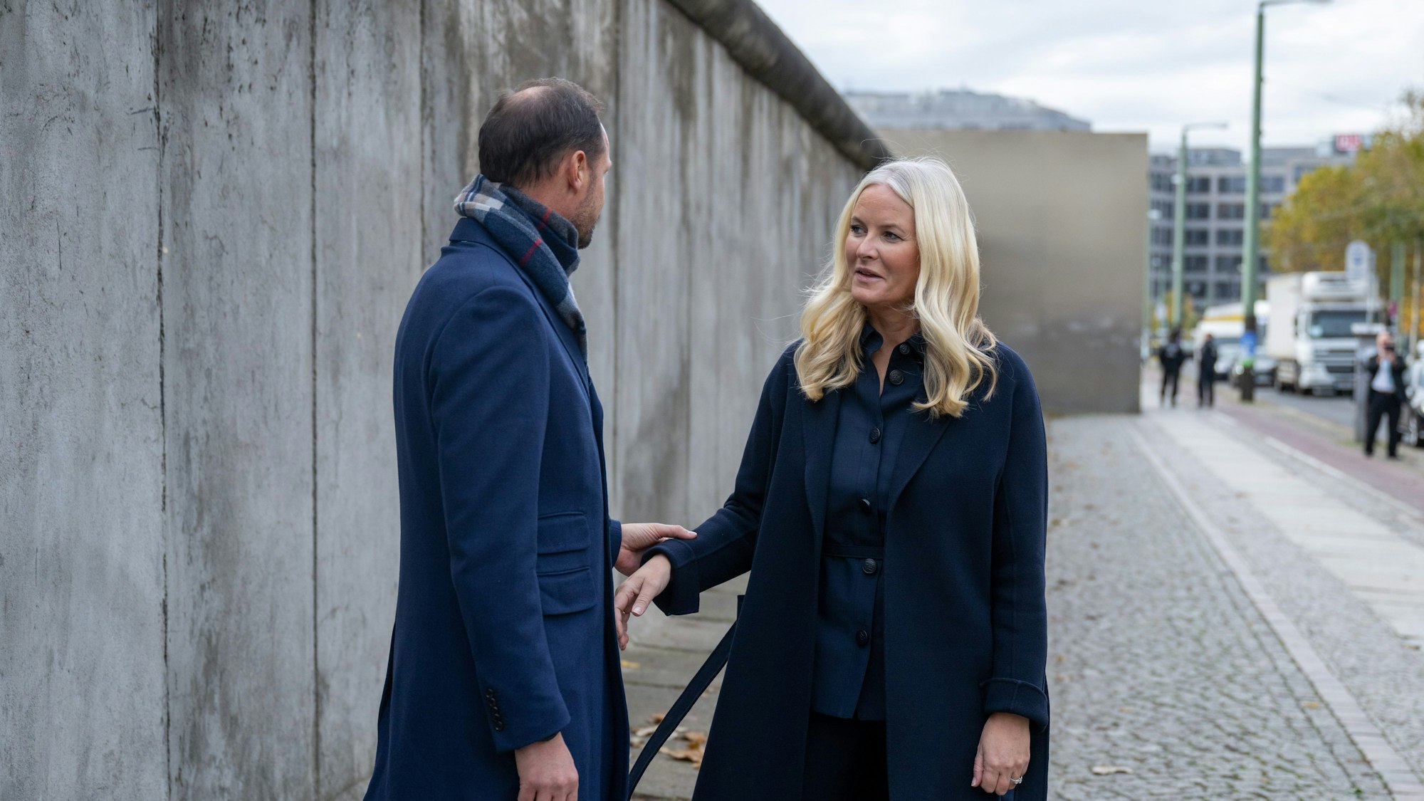 09.11.2023, Berlin: Der norwegische Kronprinz Haakon (l) und seine Frau Mette-Marit, stehen bei der Zentralen Gedenkveranstaltung des 34 vor einem Stück Mauer. Jahrestags des Mauerfalls an der Gedenkstätte Berliner Mauer. Der norwegische Kronprinz ist zu einem viertägigen Besuch nach Deutschland gekommen. Foto: Christophe Gateau/dpa +++ dpa-Bildfunk +++