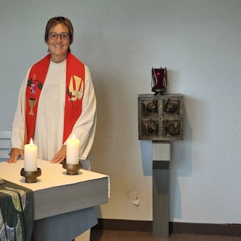 Krankenhausseelsorgerin Pfarrerin Gabriele Bach steht in Talar mit Stola an einem Altar.