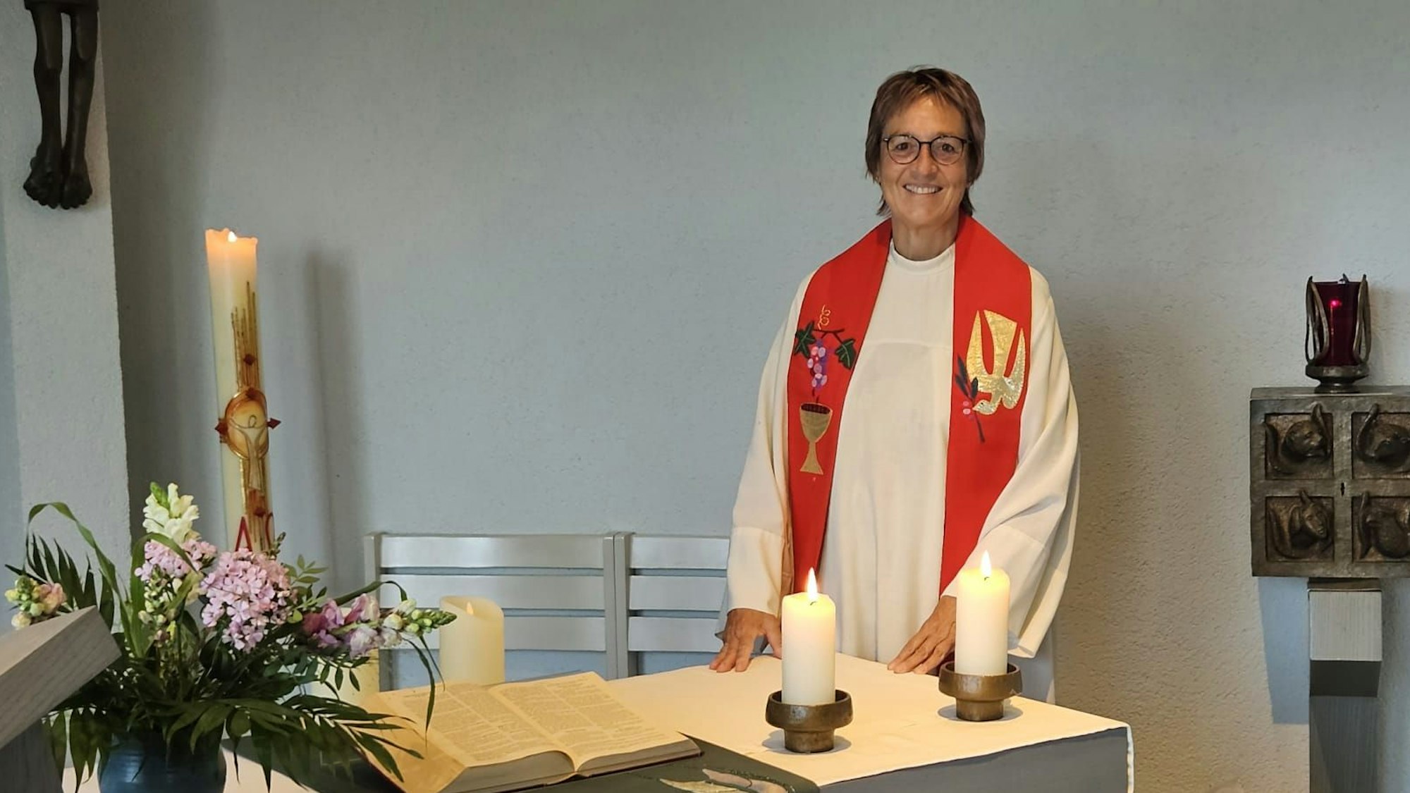 Krankenhausseelsorgerin Pfarrerin Gabriele Bach steht in Talar mit Stola an einem Altar.