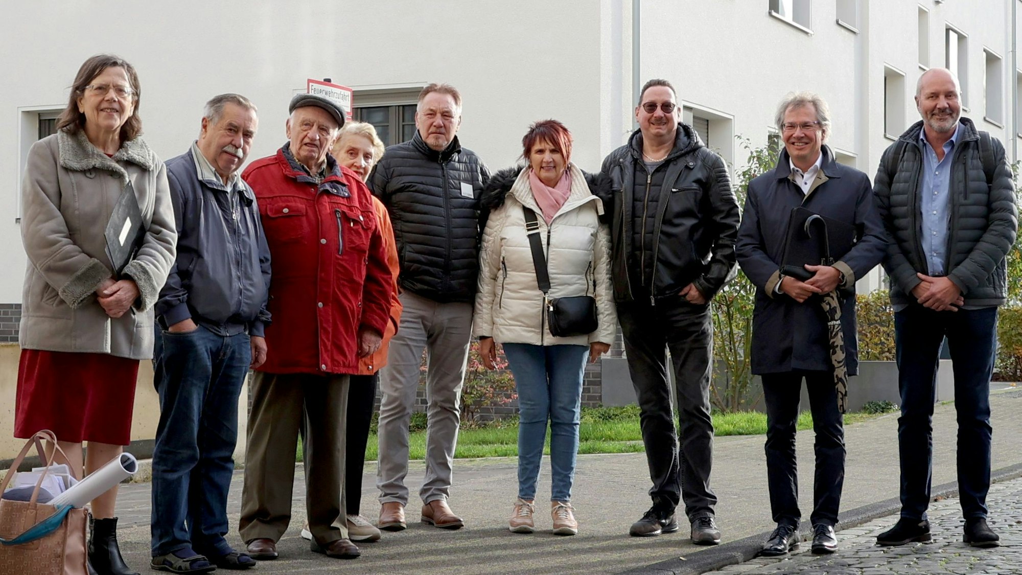 Das Foto zeigt neun Personen auf dem Gehweg einer Siedlung.