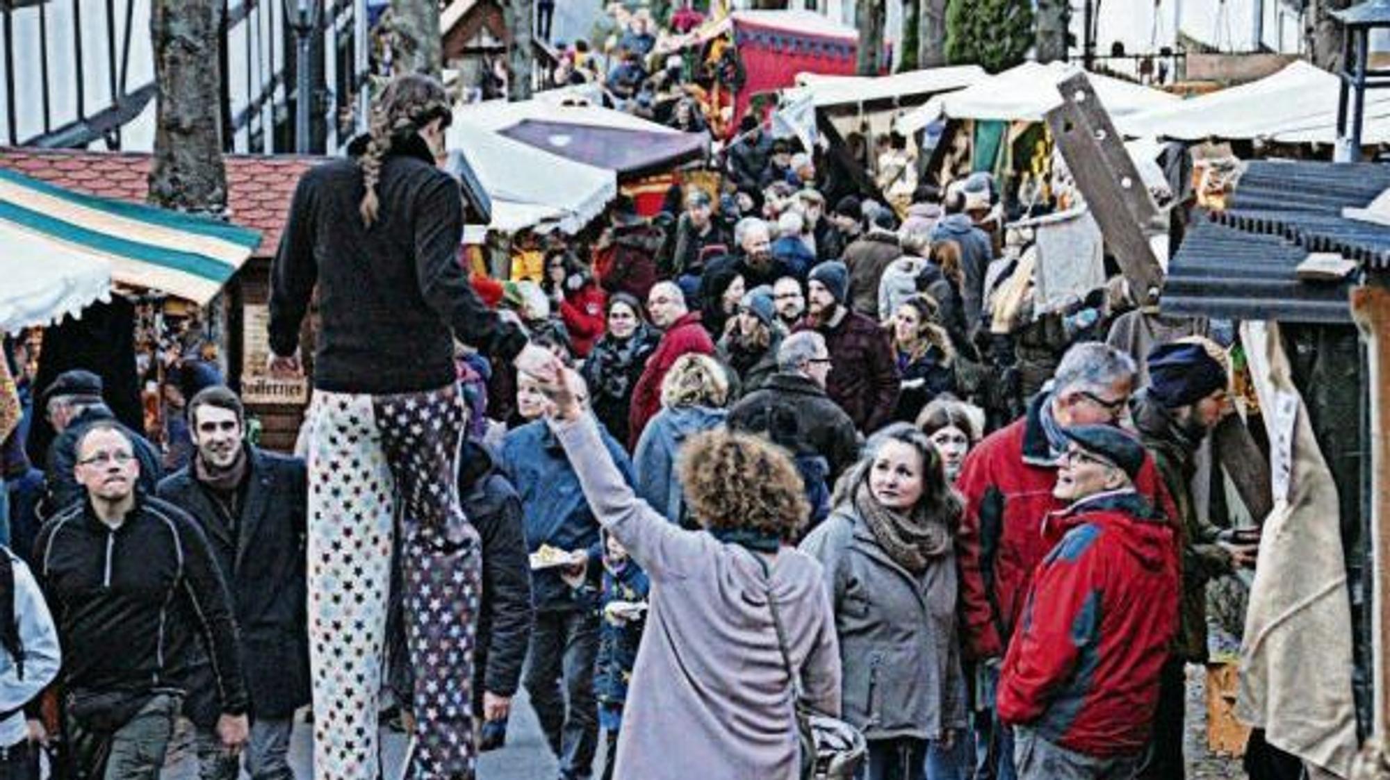 Eine Gasse in Stadt Blankenberg beim Mitttelmarkt im Jahr 2019 ist voller Besucher, dazwischen eine Stelzengängerin.