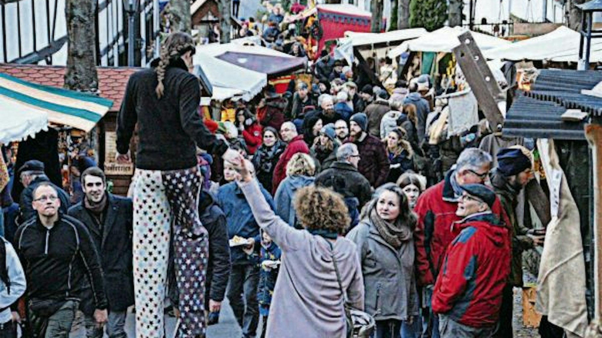 Eine Gasse in Stadt Blankenberg beim Mitttelmarkt im Jahr 2019 ist voller Besucher, dazwischen eine Stelzengängerin.