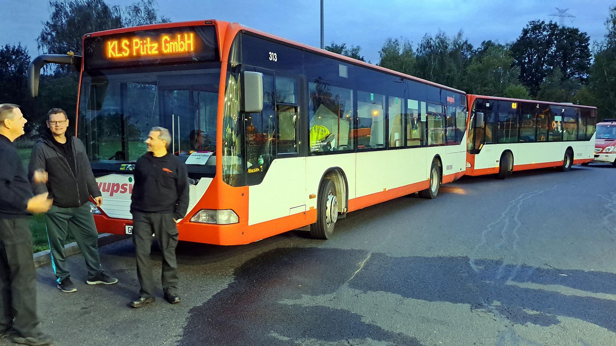 Zwei Linienbusse stehen in einer Reihe auf einem Autobahnparkplatz in Polen – auf dem Weg in die Ukraine.