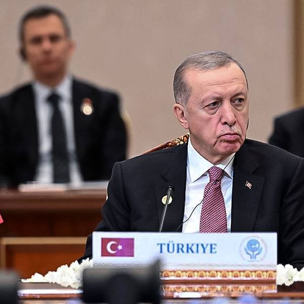 Recep Tayyip Erdogan, Präsident der Türkei, sitzt im Vordergrund an einem Pult mit der Aufschrift „Türkiye“, im Hintergrund sind andere Staats- und Regierungschefs zu sehen.