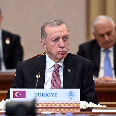 Recep Tayyip Erdogan, Präsident der Türkei, sitzt im Vordergrund an einem Pult mit der Aufschrift „Türkiye“, im Hintergrund sind andere Staats- und Regierungschefs zu sehen.