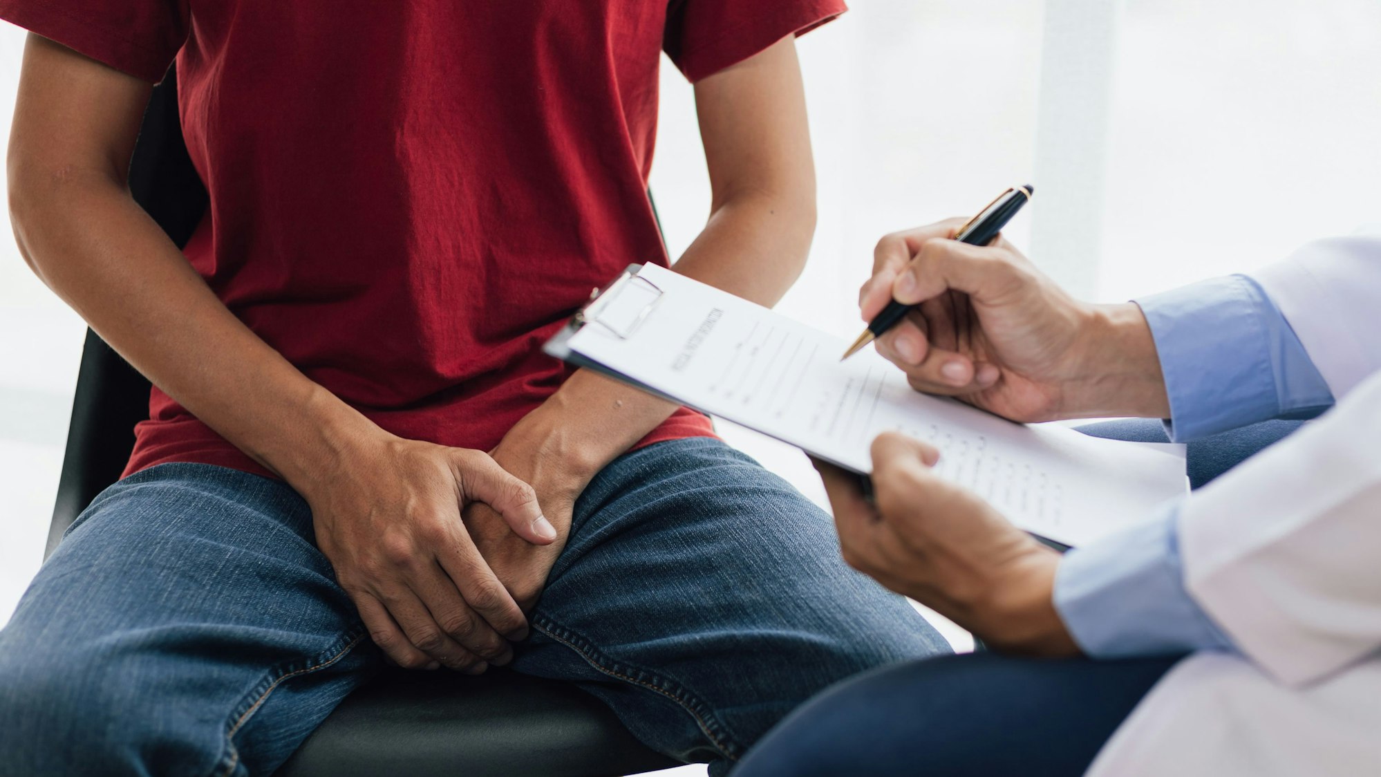 Junge sitzt mit Händen im Schoß beim Arzt