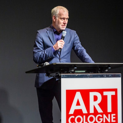 Daniel Hug steht mit Mikrofon an einem Stehpult.