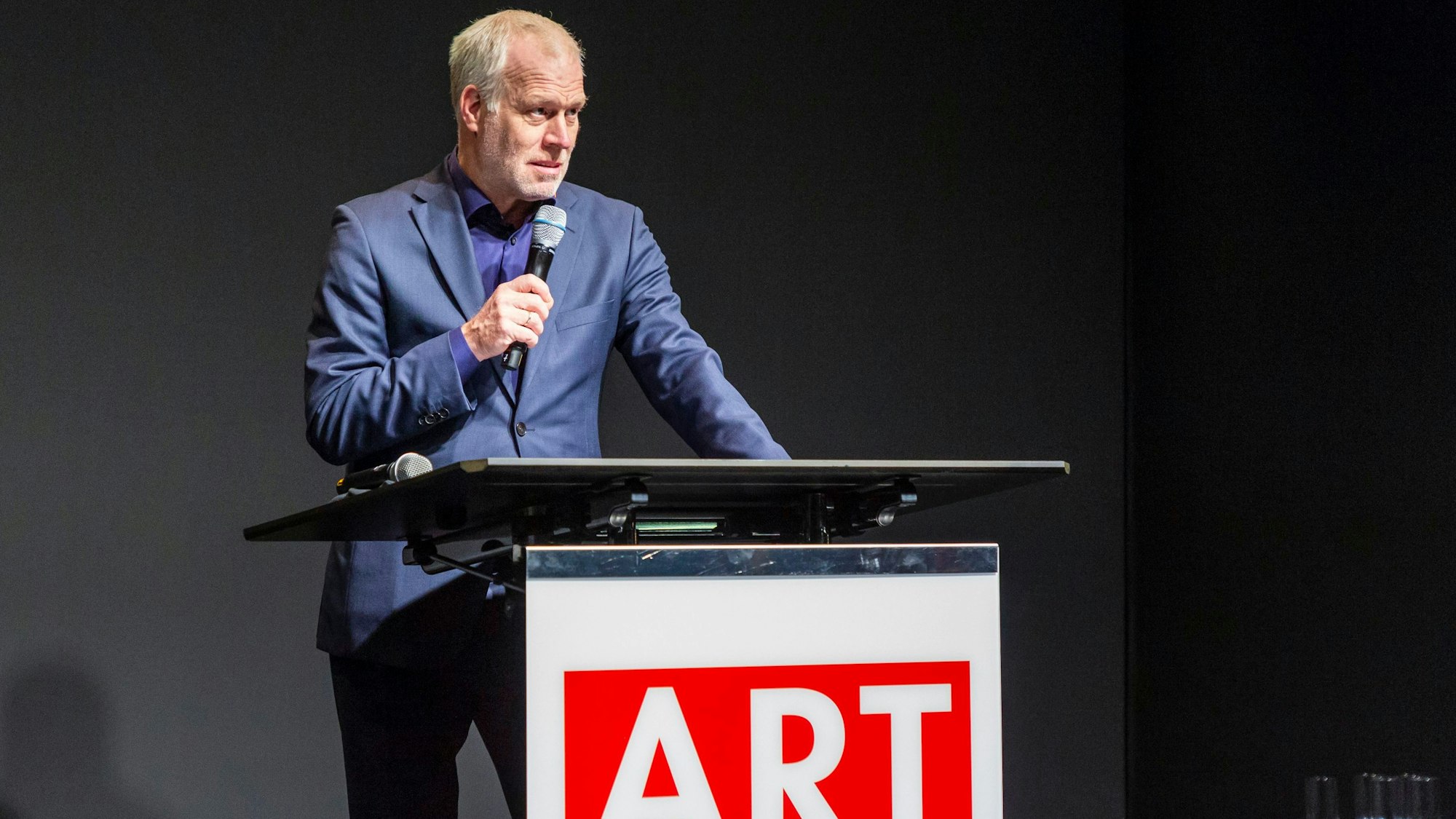 Daniel Hug steht mit Mikrofon an einem Stehpult.