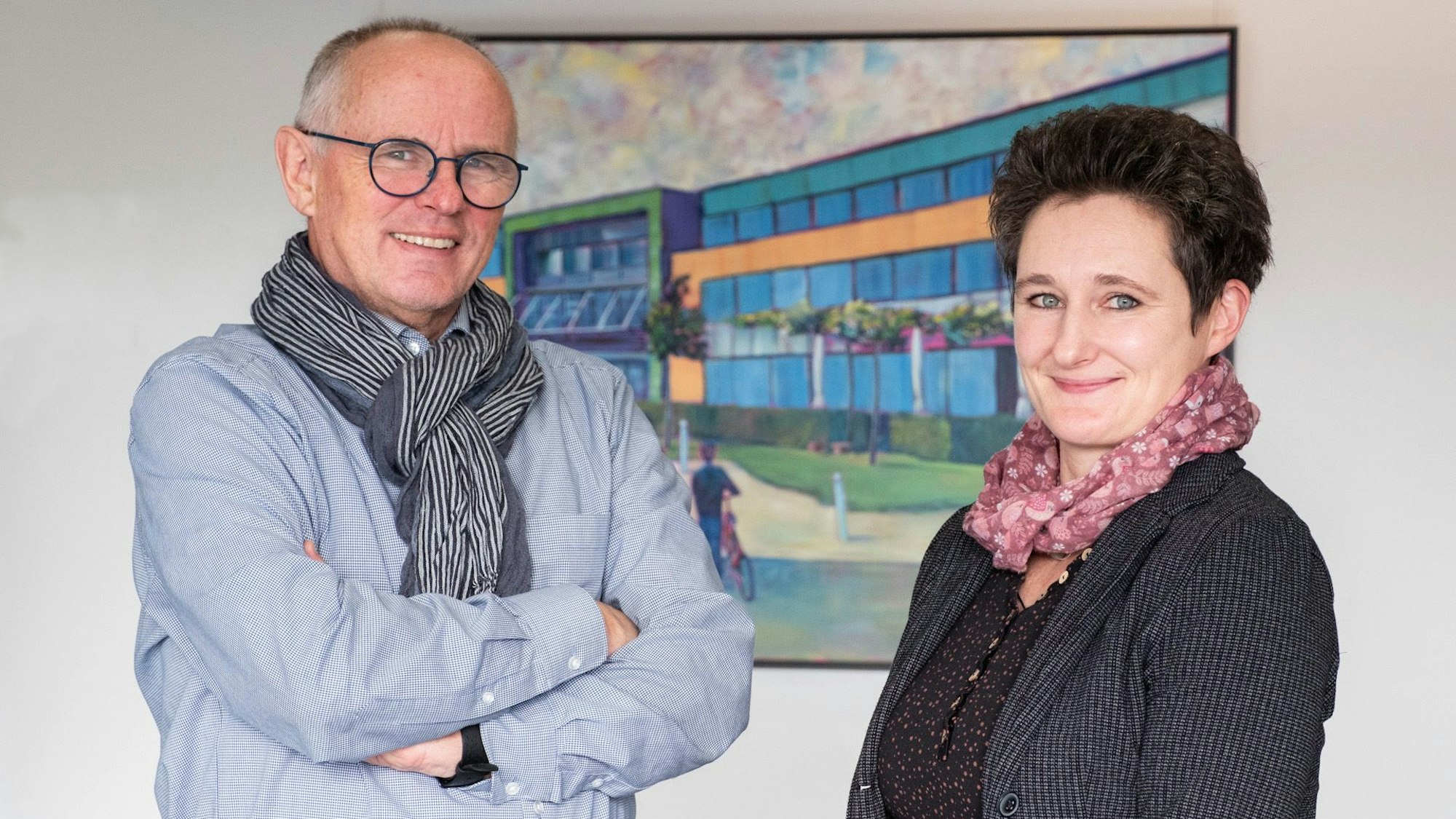 Dezernent Ralf Claßen und Fachbereichsleiterin Kati Jakob stehen vor einem Bild, das das Rathaus Mechernich zeigt.