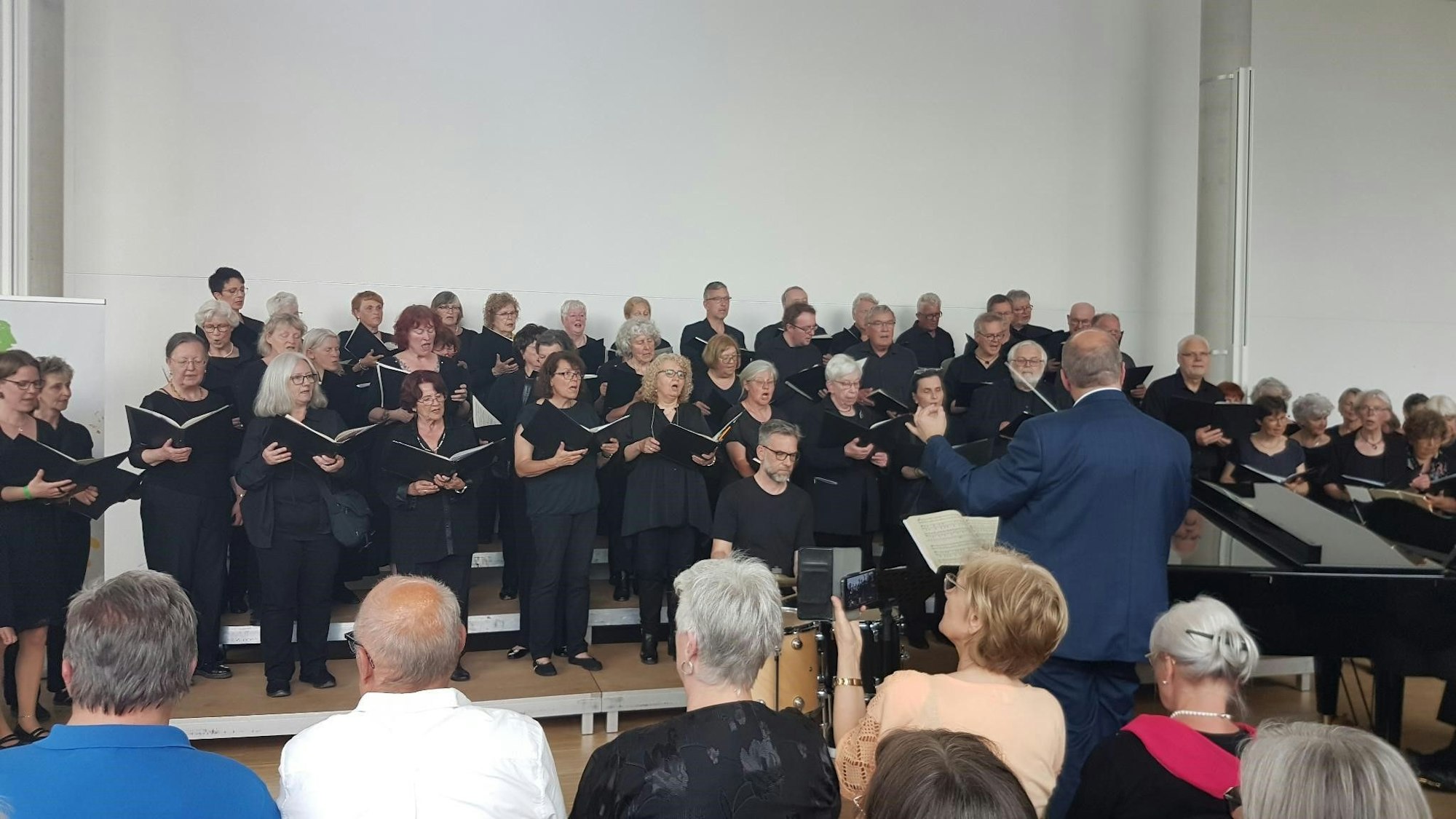 Ein Chor steht auf einer Bühne und singt vor Publikum.
