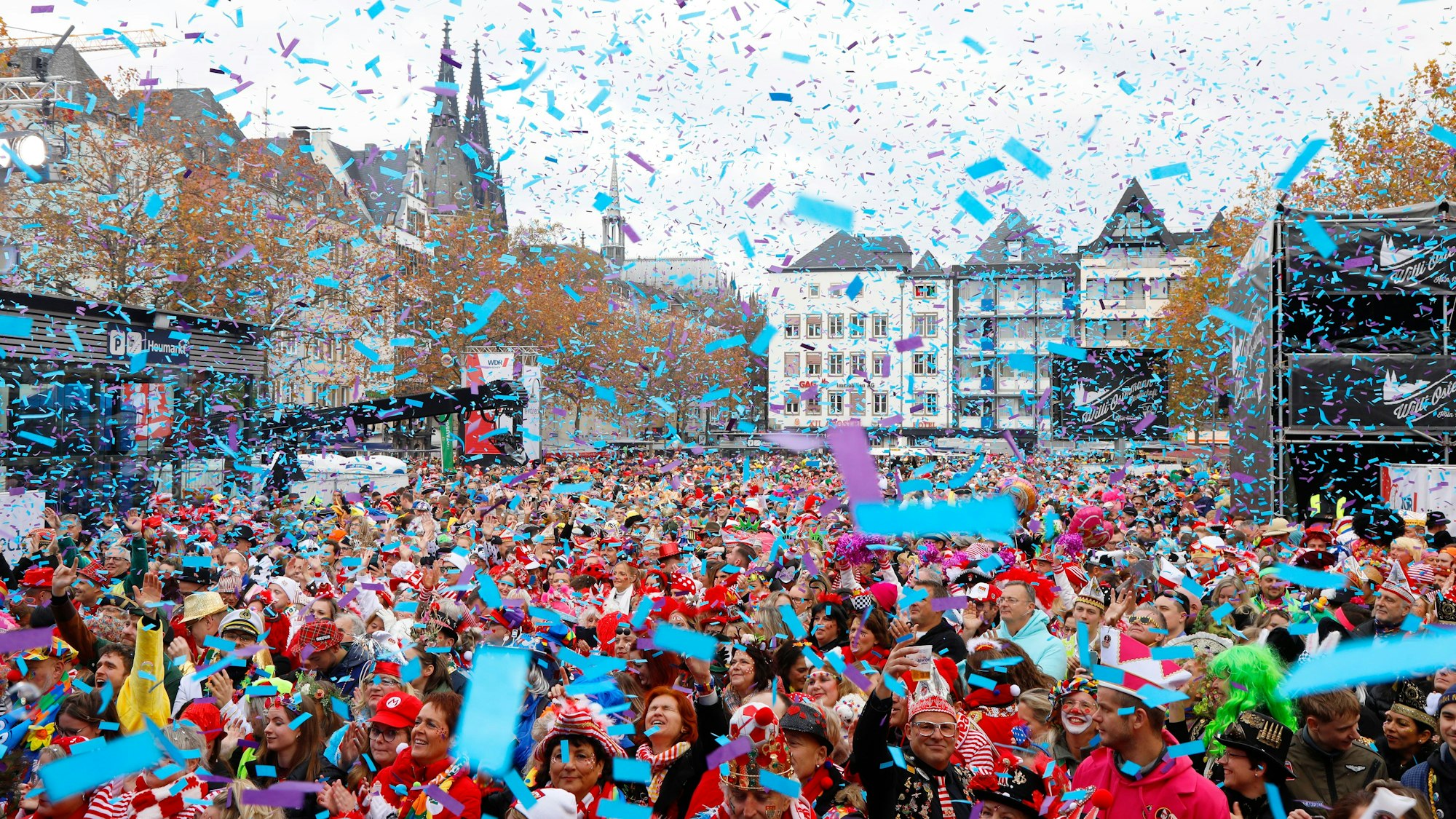 Menschen feiern im Konfetti-Regen auf dem Heumarkt Karneval.