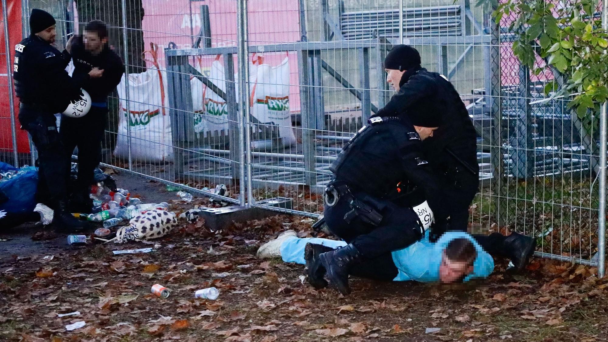 Polizeibeamte fixieren am Abend eine Person in der Nähe des Aachener Weihers auf dem Boden.