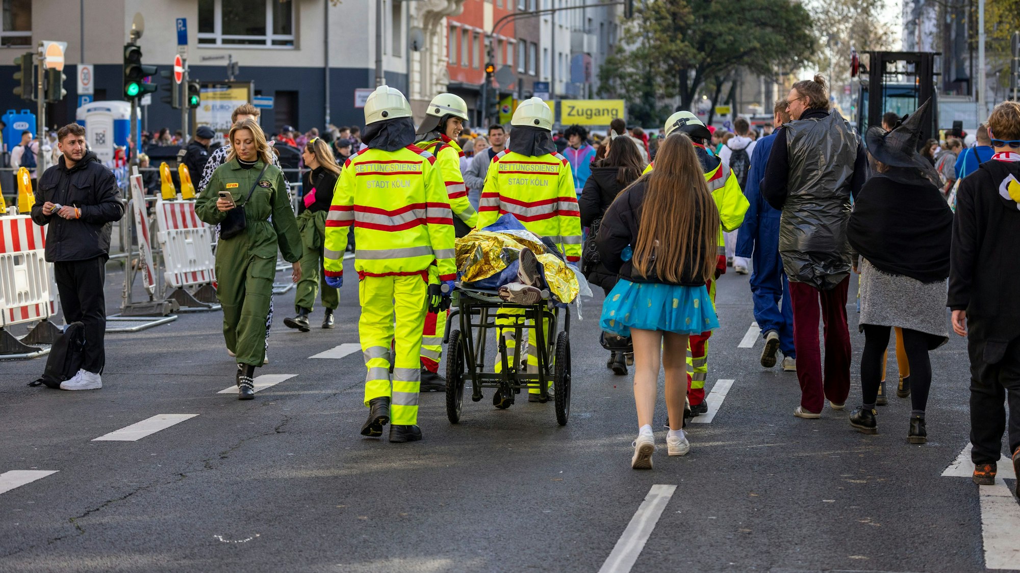 Auf einer Bahre wird ein alkoholisiertes Karnevalist von Sanitätern transportiert.