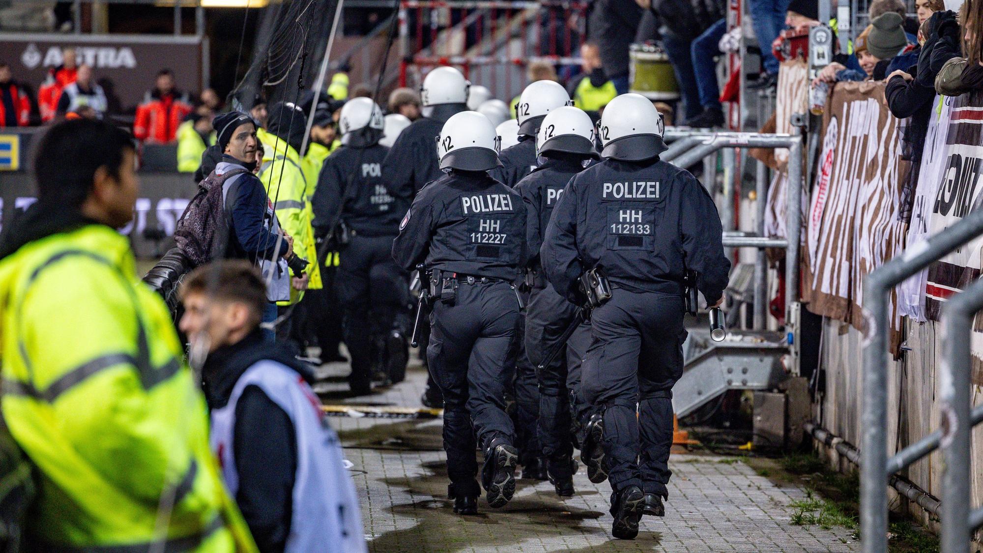 10.11.2023, Hamburg: Fußball: 2. Bundesliga, FC St. Pauli - Hannover 96, 13. Spieltag, Millerntorstadion. Einsatzkräfte der Polizei laufen auf den Fanblock der Hannoveraner zu. Foto: Axel Heimken/dpa - WICHTIGER HINWEIS: Gemäß den Vorgaben der DFL Deutsche Fußball Liga bzw. des DFB Deutscher Fußball-Bund ist es untersagt, in dem Stadion und/oder vom Spiel angefertigte Fotoaufnahmen in Form von Sequenzbildern und/oder videoähnlichen Fotostrecken zu verwerten bzw. verwerten zu lassen. +++ dpa-Bildfunk +++