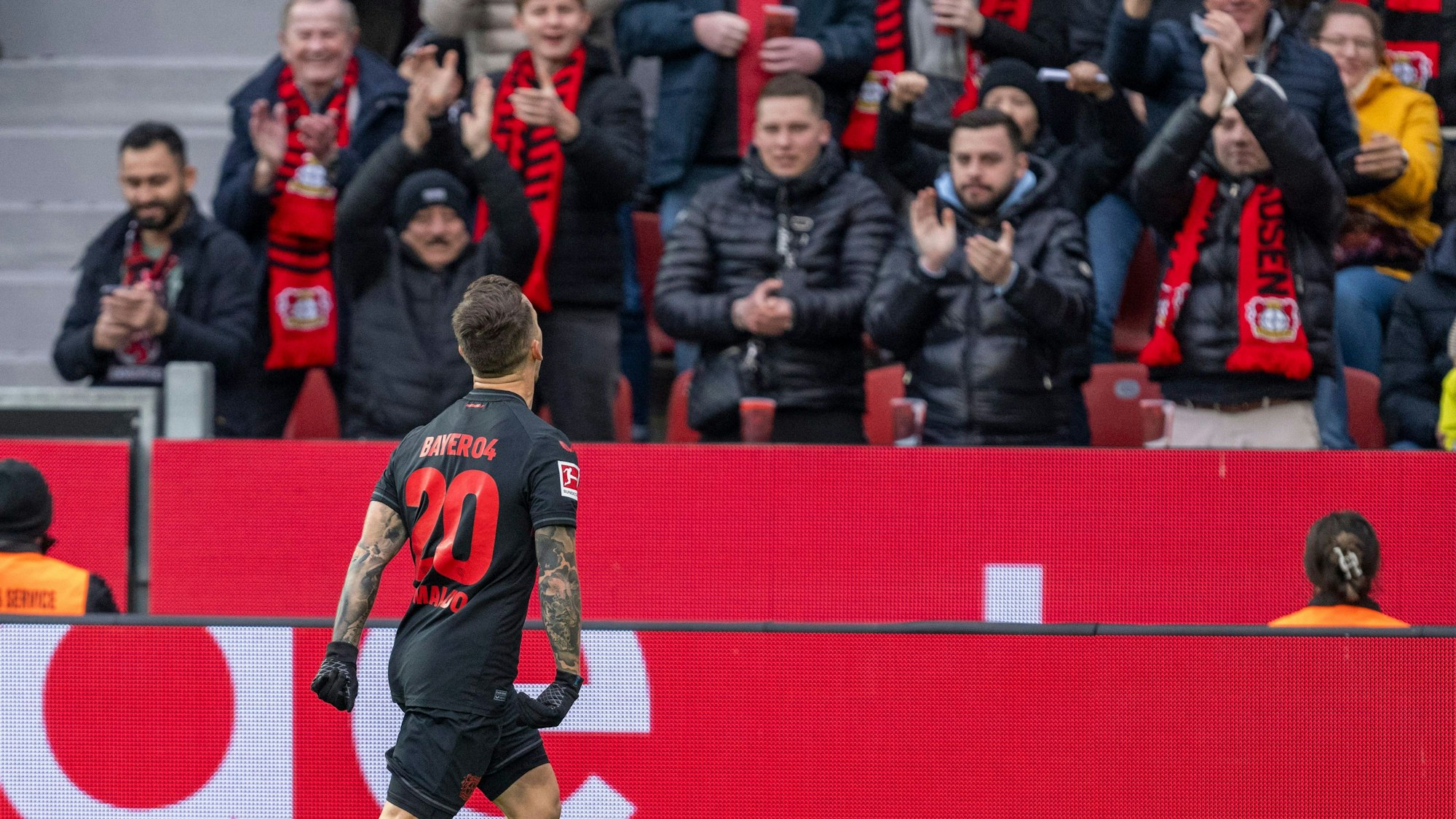 Leverkusens Alejandro Grimaldo jubelt nach seinem Tor zum 1:0. Im Hintergrund sind Bayer-Fans zu sehen.