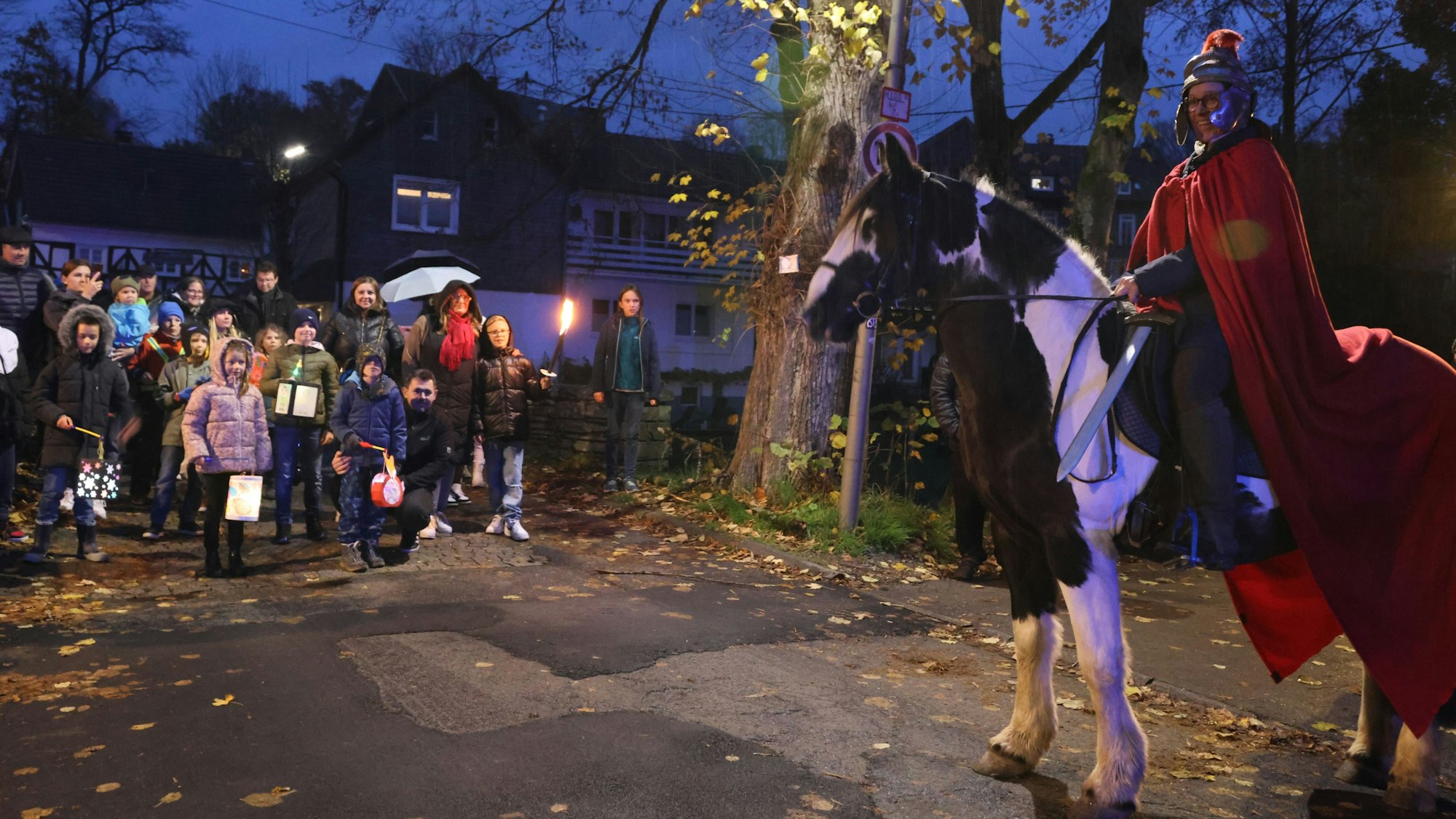 Ein Martinsumzug mit Kindern und einem St- Martin auf einem Pferd.