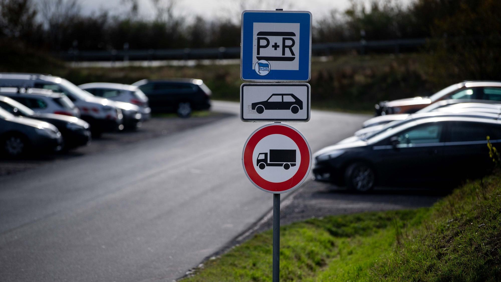 Das Bild zeigt den Pendlerparkplatz in Weilerswist. Zu sehen sind mehrere Schilder und im Hintergrund geparkte Autos.